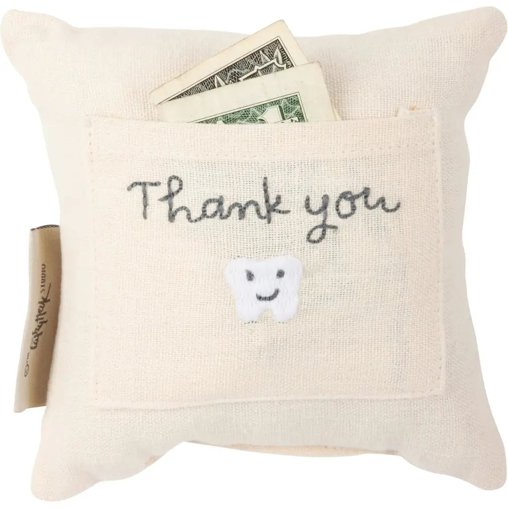 Off-white tooth fairy pillow with thank you embroidered pocket and smiling tooth holding dollar bills