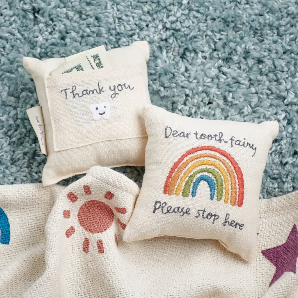 Cream-colored rainbow tooth fairy pillow with embroidered plea