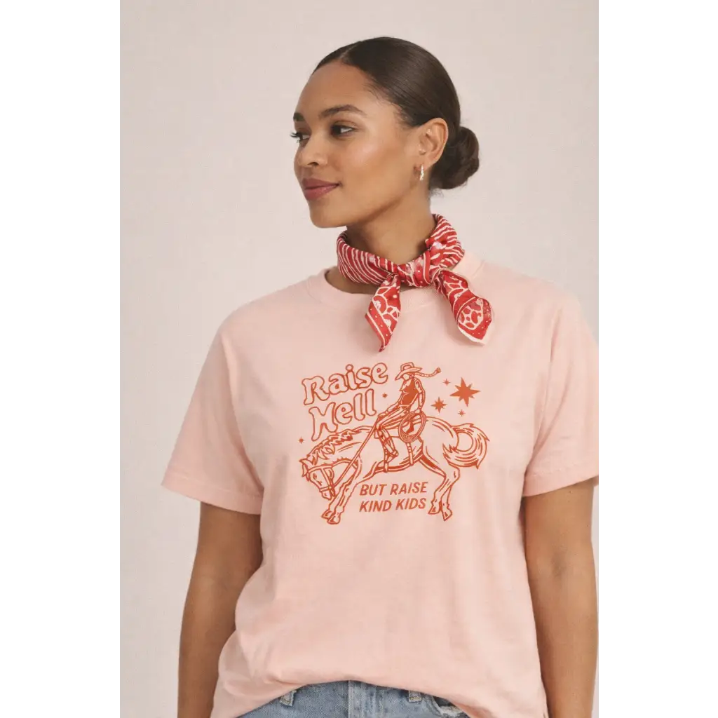 Oversized unisex tee with orange cowboy graphic and raise well but raise kind kids text
