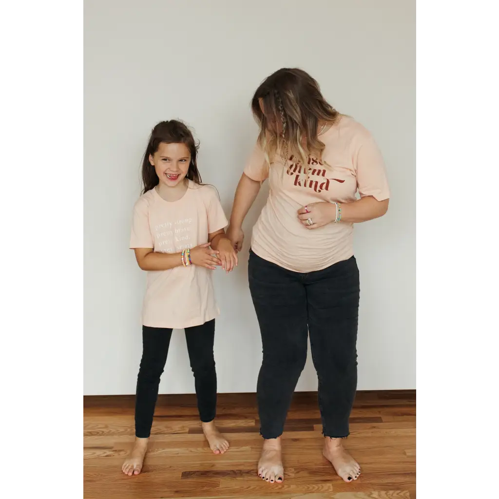 Two people in matching peach organic cotton graphic t-shirts, styled casually