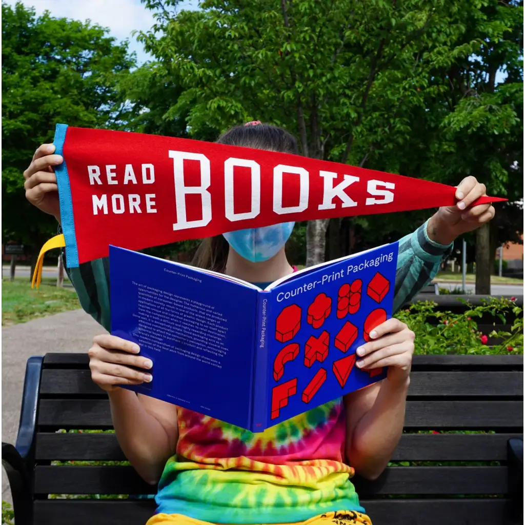 Person reading a book with a Read More Books Pennant Flag, perfect for stylish womens clothes