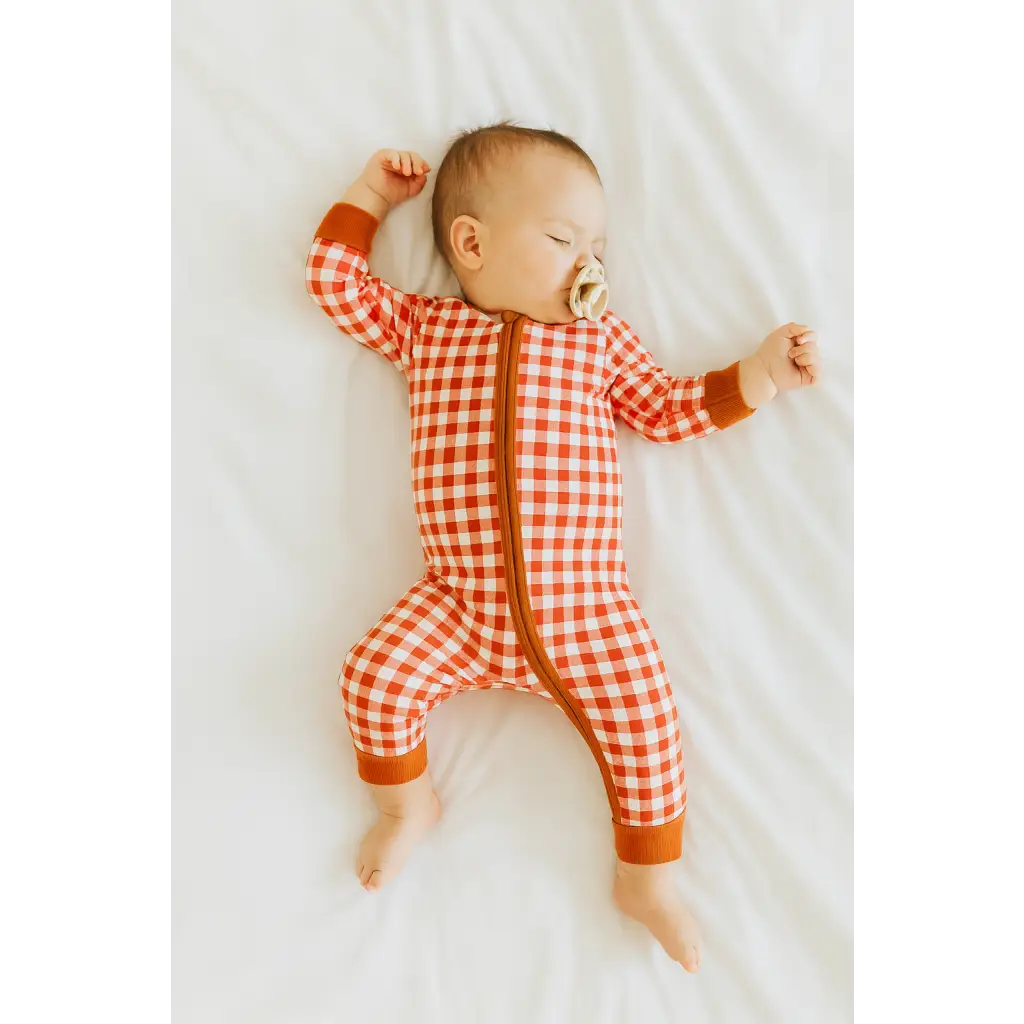 Sleeping baby in a red gingham bamboo baby sleeper with a zipper