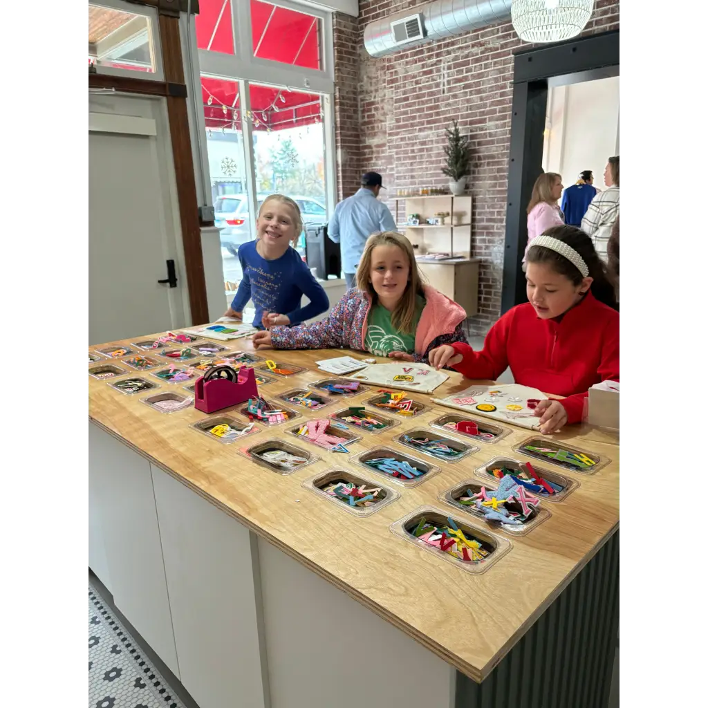 Kids at a craft bar exploring polished prints with stylish women’s clothes nearby