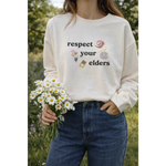 Cream-colored Respect Your Elders pullover with polished prints and broken-in feel