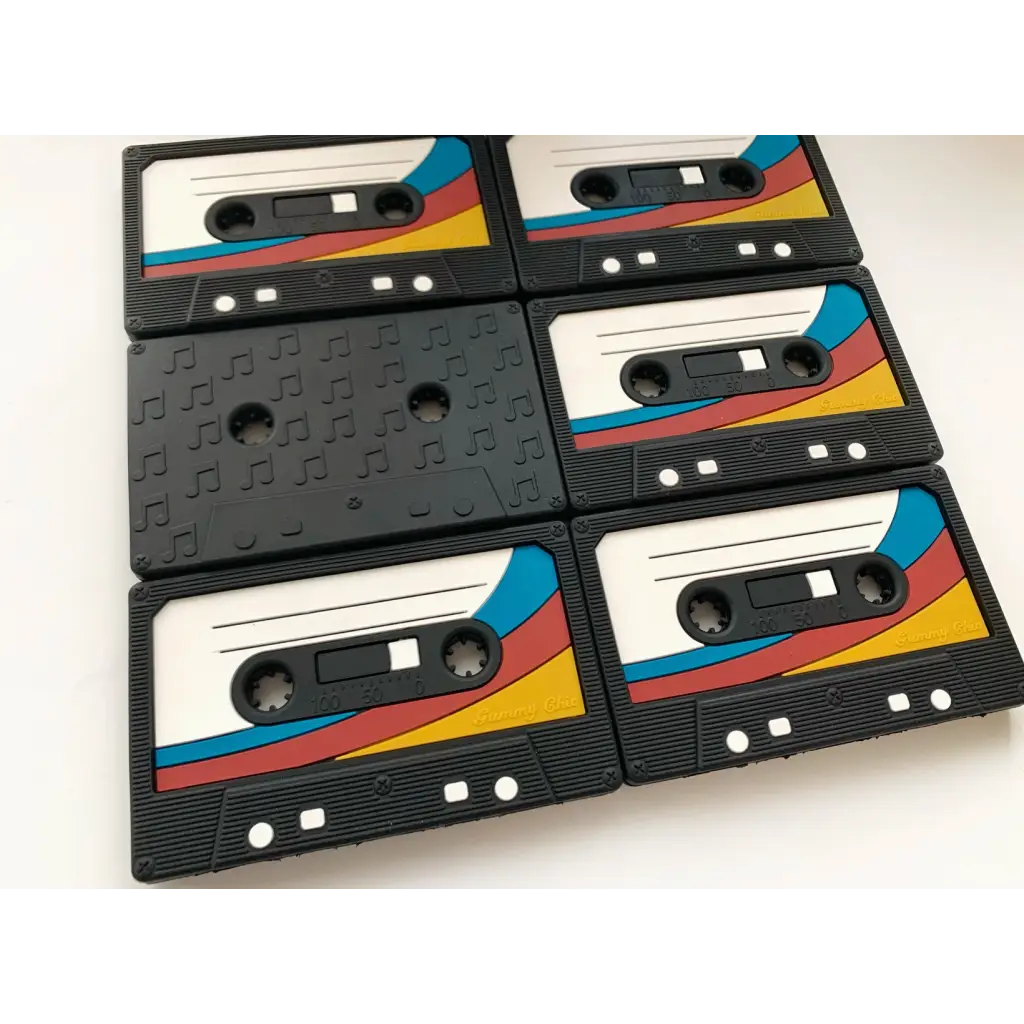 Retro cassette tape teether featuring black tapes with colorful diagonal stripes