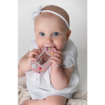 Cute pink video game inspired silicone teether being chewed on by a happy baby