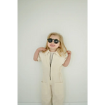 Person in a cream jumpsuit rocking adorable round sunglasses for a stylish summer look