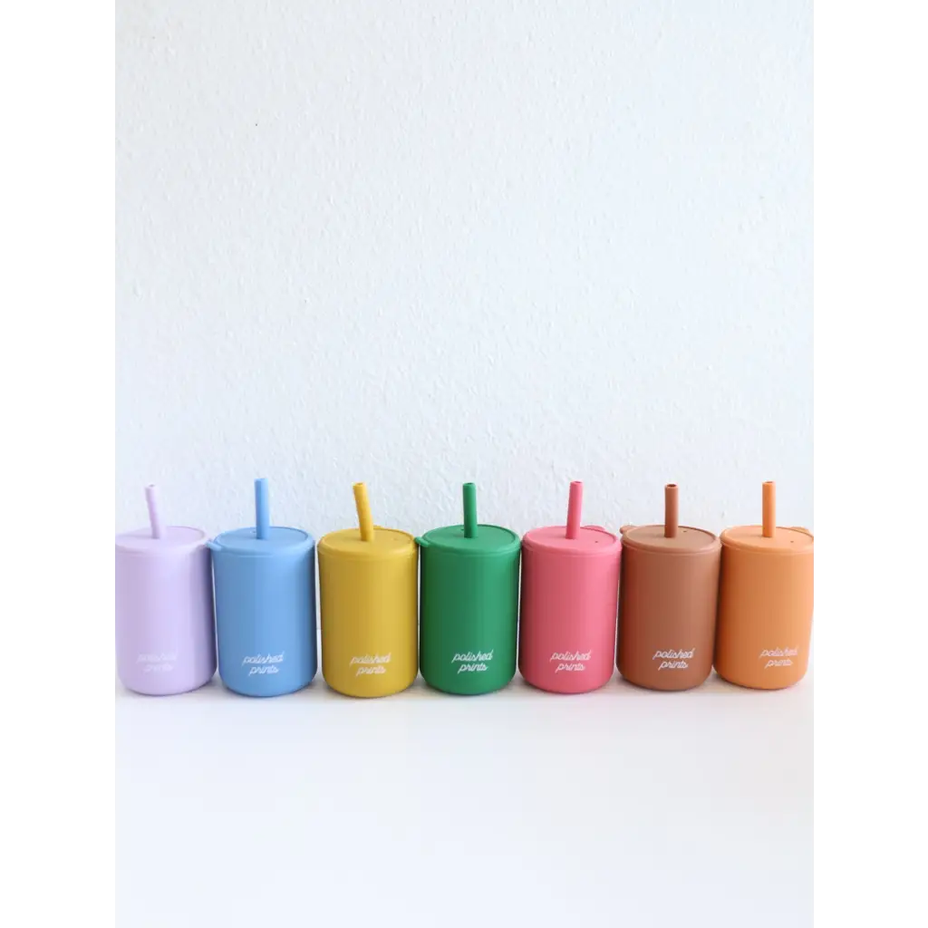 Seven colorful mini silicone straw cups for kids arranged in a fun rainbow sequence