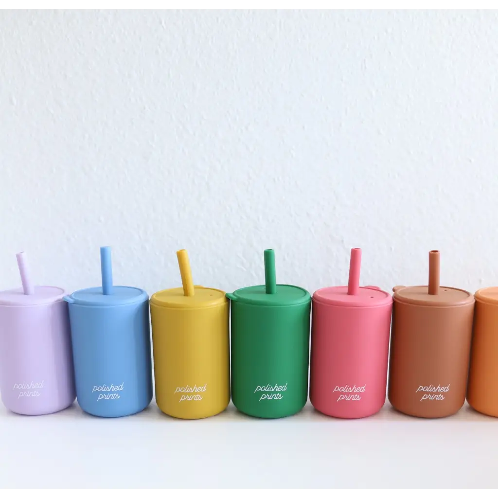 Colorful silicone straw cups with lids arranged in a rainbow, featuring mini silicone straws