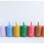 Colorful silicone straw cups with lids arranged in a rainbow, featuring mini silicone straws