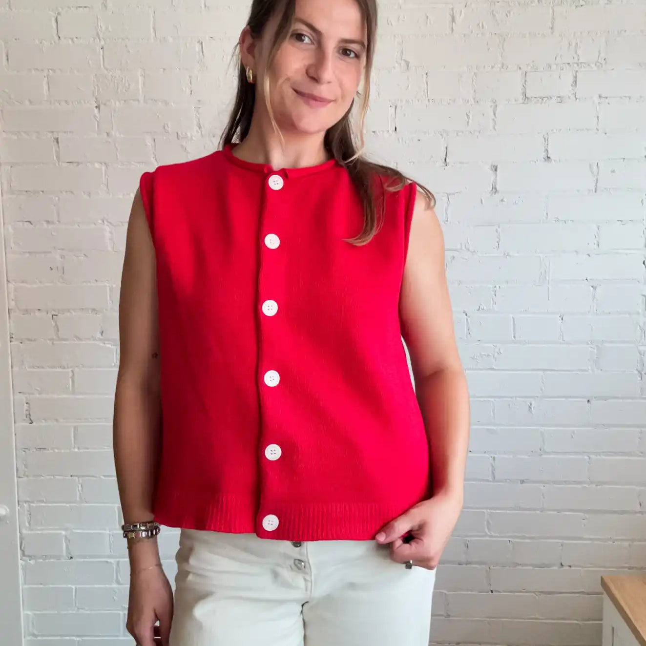 A sleeveless red button-up top with white buttons.