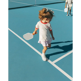 Young tennis player in white outfit with racquet wearing Soft Girls Club Ringer Tee