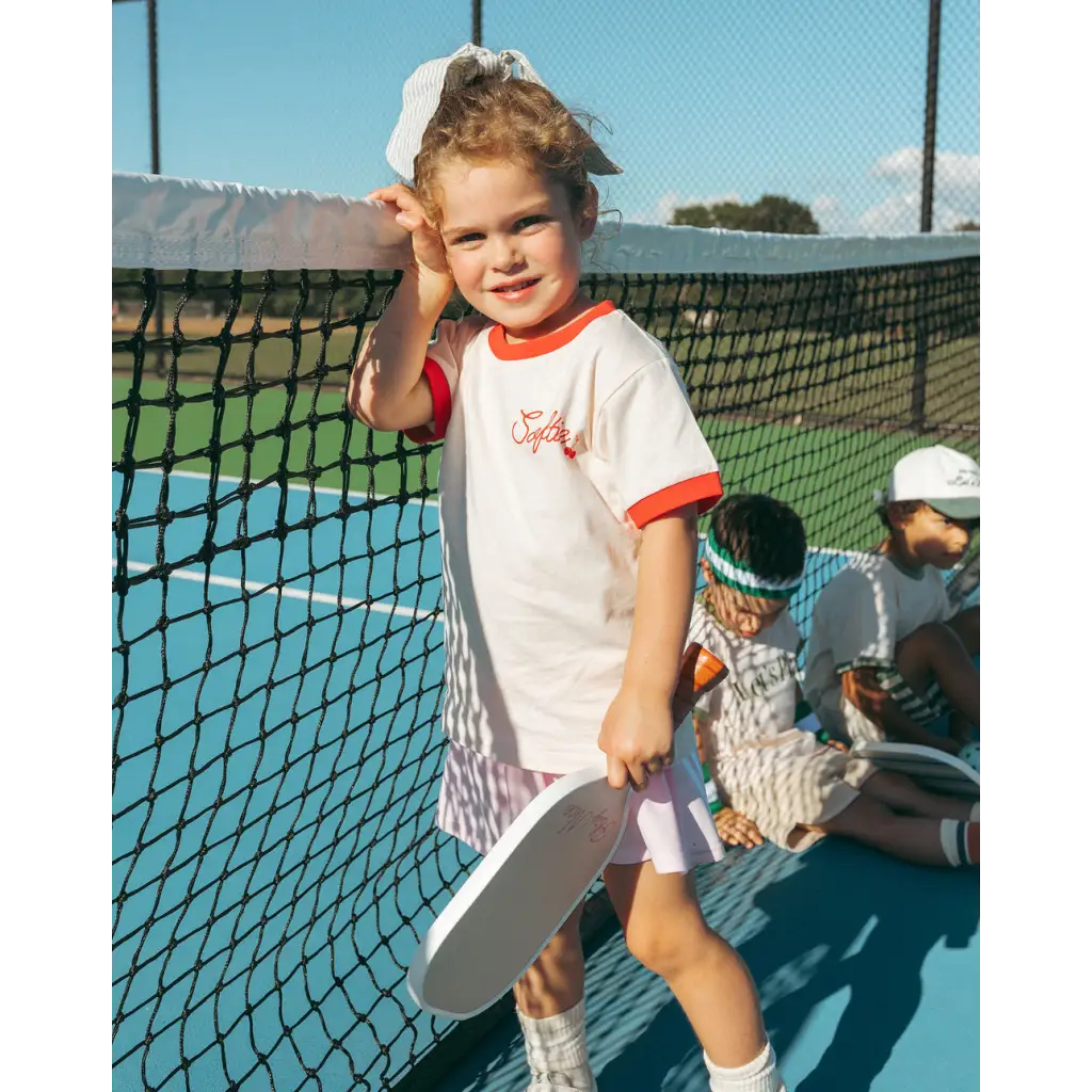 Young tennis player in Soft Girls Club Ringer Tee with red trim on the court