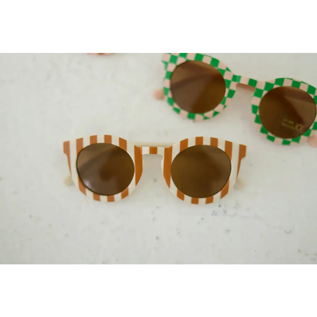 Two pairs of striped baby sunglasses with brown lenses for kids to show off one’s style