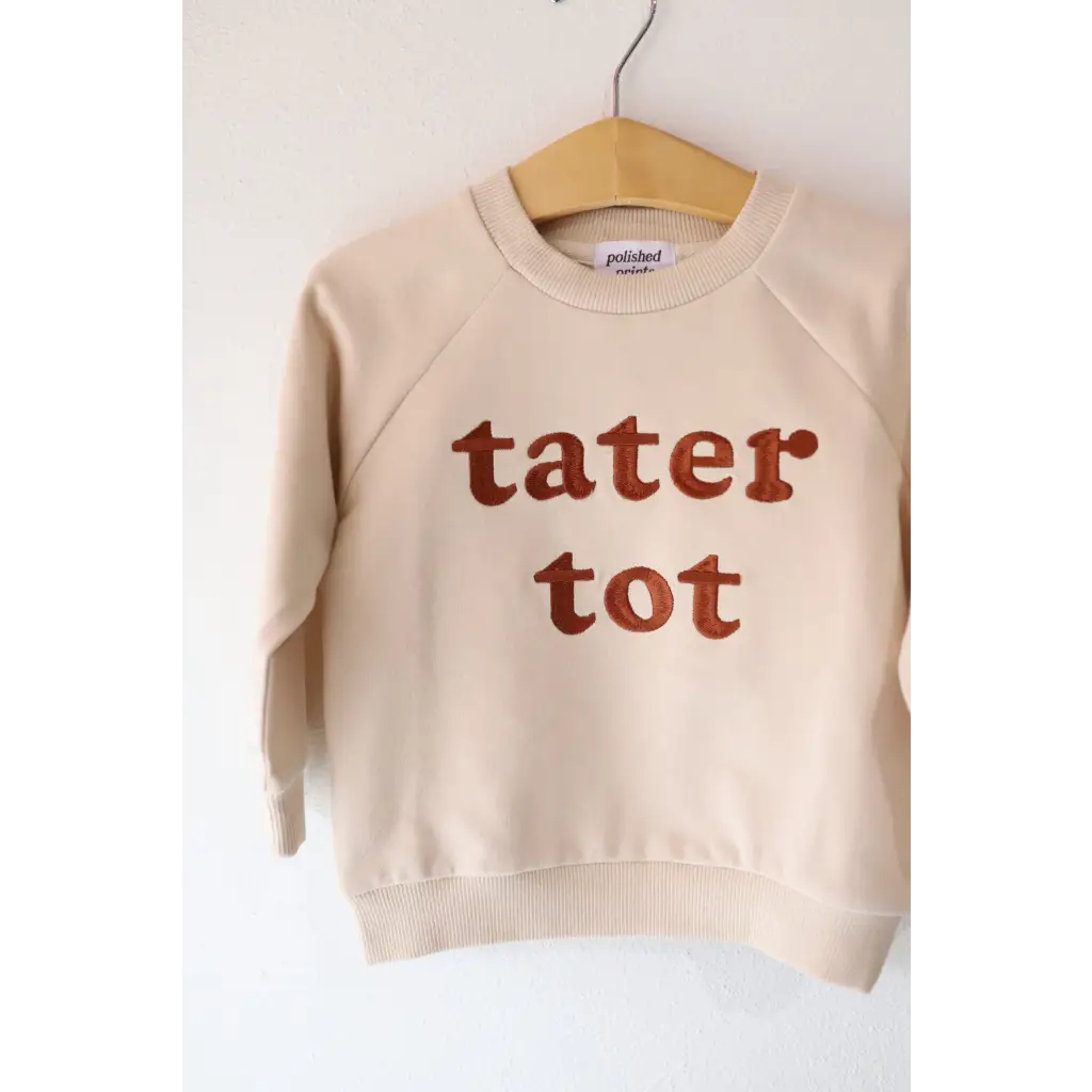 Cream Tater Tot Kids Pullover Sweatshirt on a hanger with cute brown lettering