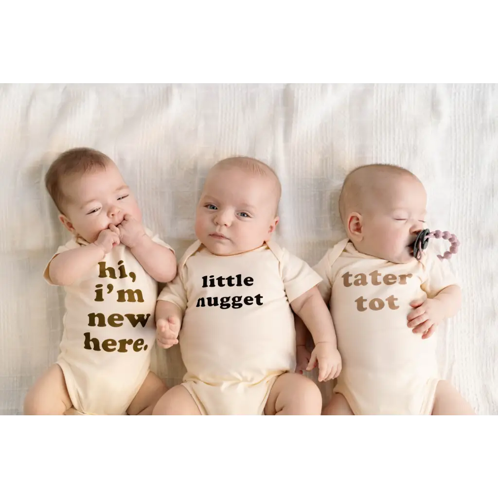 Three babies in cream organic cotton onesies with fun messages, perfect for Tater Tot Organic