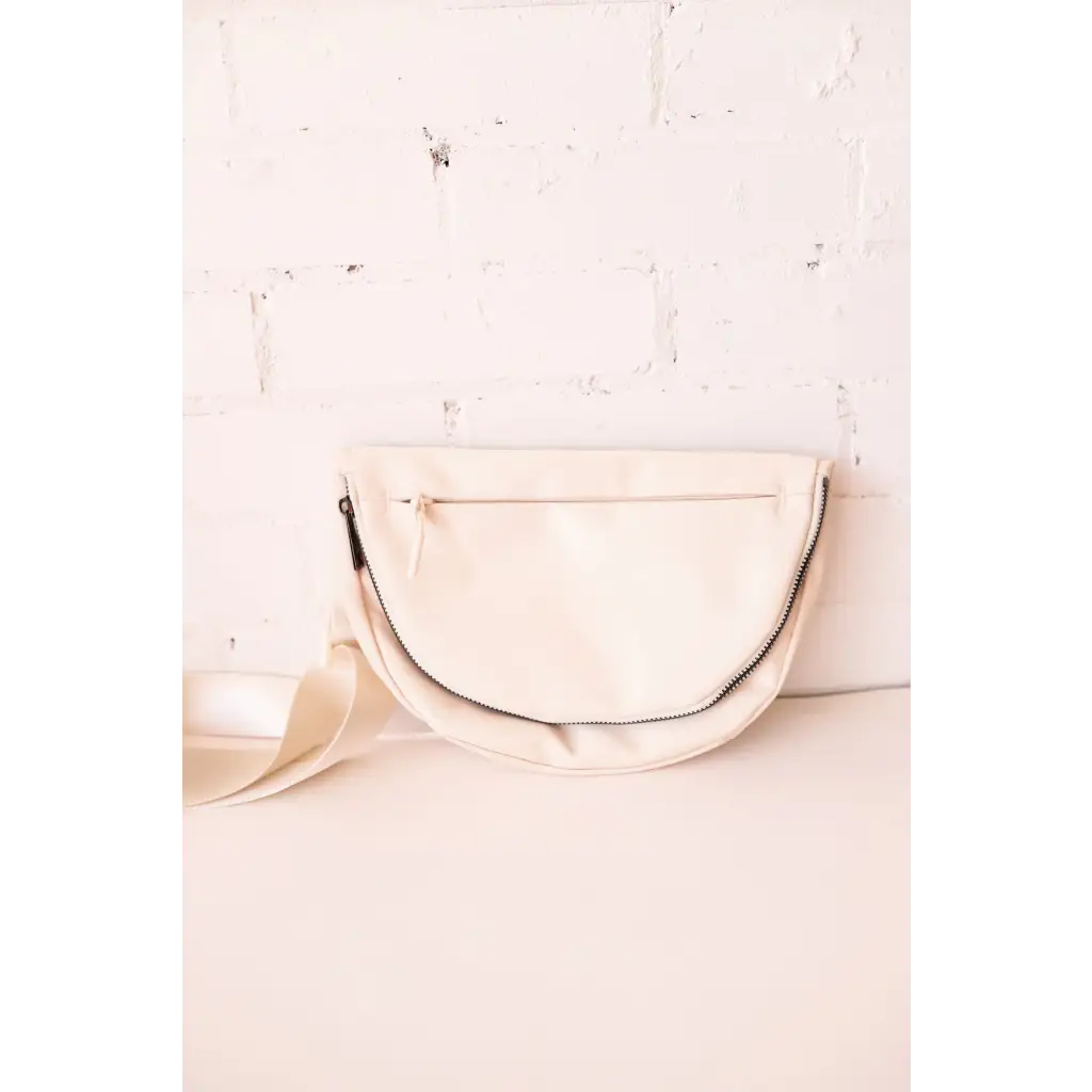 Cream-colored half-moon bag with zipper, perfect stylish accessory for moms and polished prints