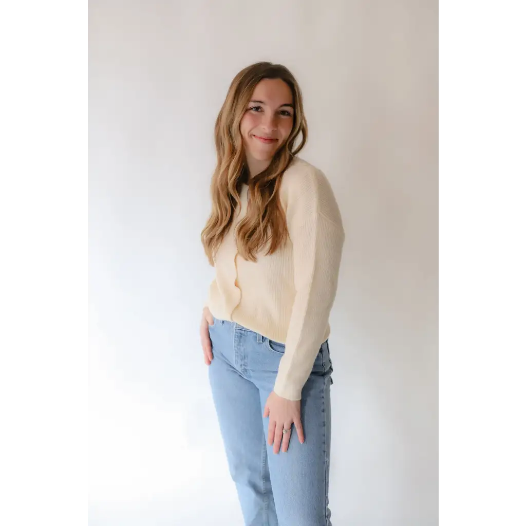 Person in a cream Annie Cardigan Sweater and light blue jeans looking stylish