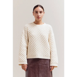 Cream-colored Betsy Crew Knit sweater with textured pattern and ribbed cuffs