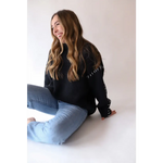 Person in a black Brandi Contrast Sweater and jeans laughing on the floor