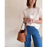 Woman enjoying coffee with The Brooke Everyday Bucket Bag in brown leather