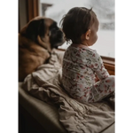 Child and pug snuggled up on a couch with a cozy organic cotton blanket in tan