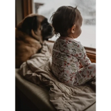 Child and pug snuggled up on a couch with a cozy organic cotton blanket in tan