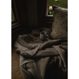 Rumpled gray blanket and coffee mug next to Cozy Premium Organic Cotton Blanket in Tan