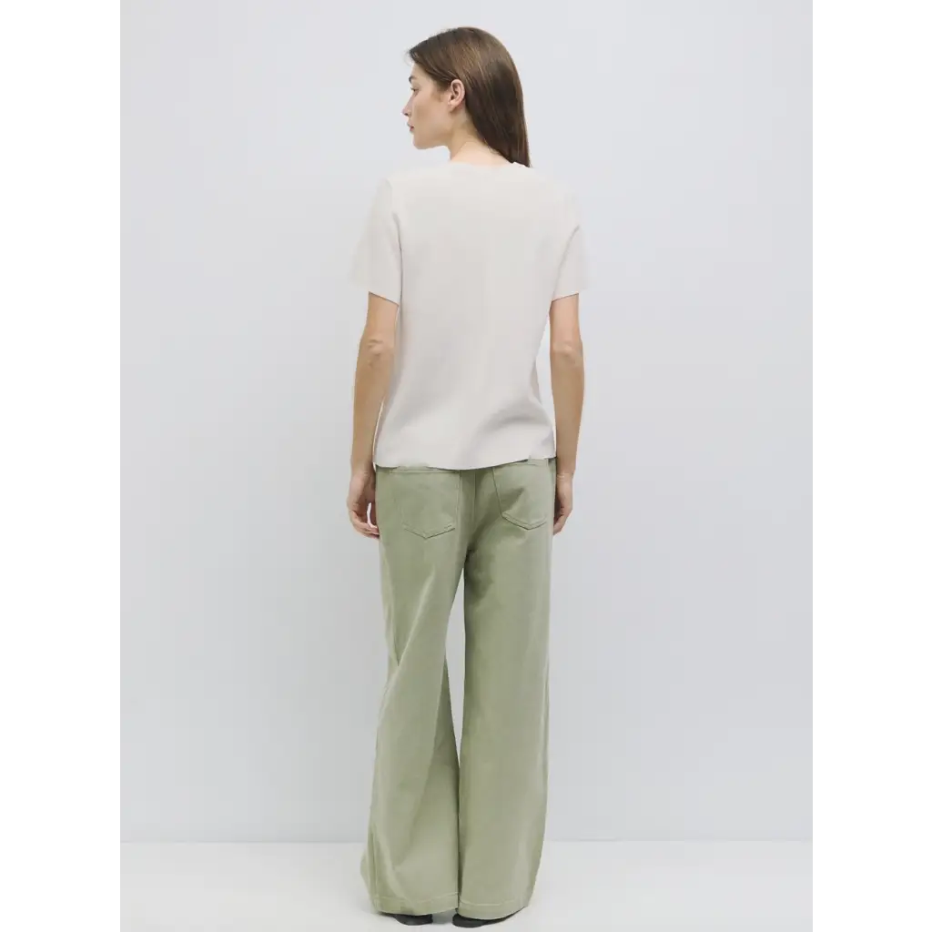 Woman in light t-shirt and wide-leg green pants from stylish womens clothes collection