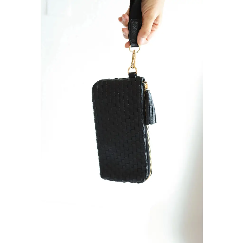 Black leather Devin Clutch with tassel held in hand, the perfect combination of style