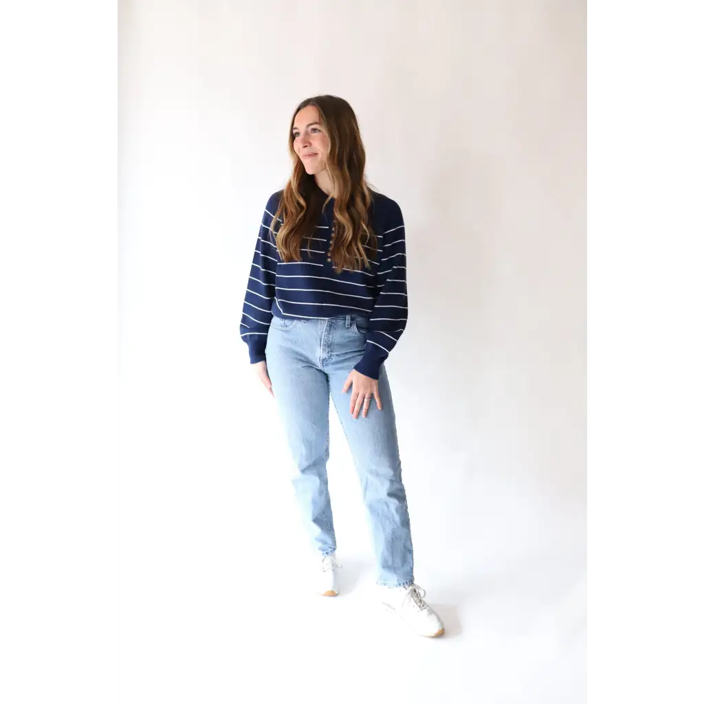 Person in The Ellen Henley Sweater in Navy with peace signs camp vibe and light blue jeans