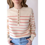 Cream-colored striped sweater with red lines and buttons, perfect for peace signs camp vibes