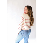 Person in red-striped white sweater and light blue jeans with peace signs camp vibe