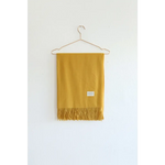 Mustard Yellow Essential Wool Blend Scarf with Fringe hanging on a wire hanger