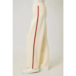 Cream-colored tracksuit pants with red stripes and elastic waistband, perfect for casual style