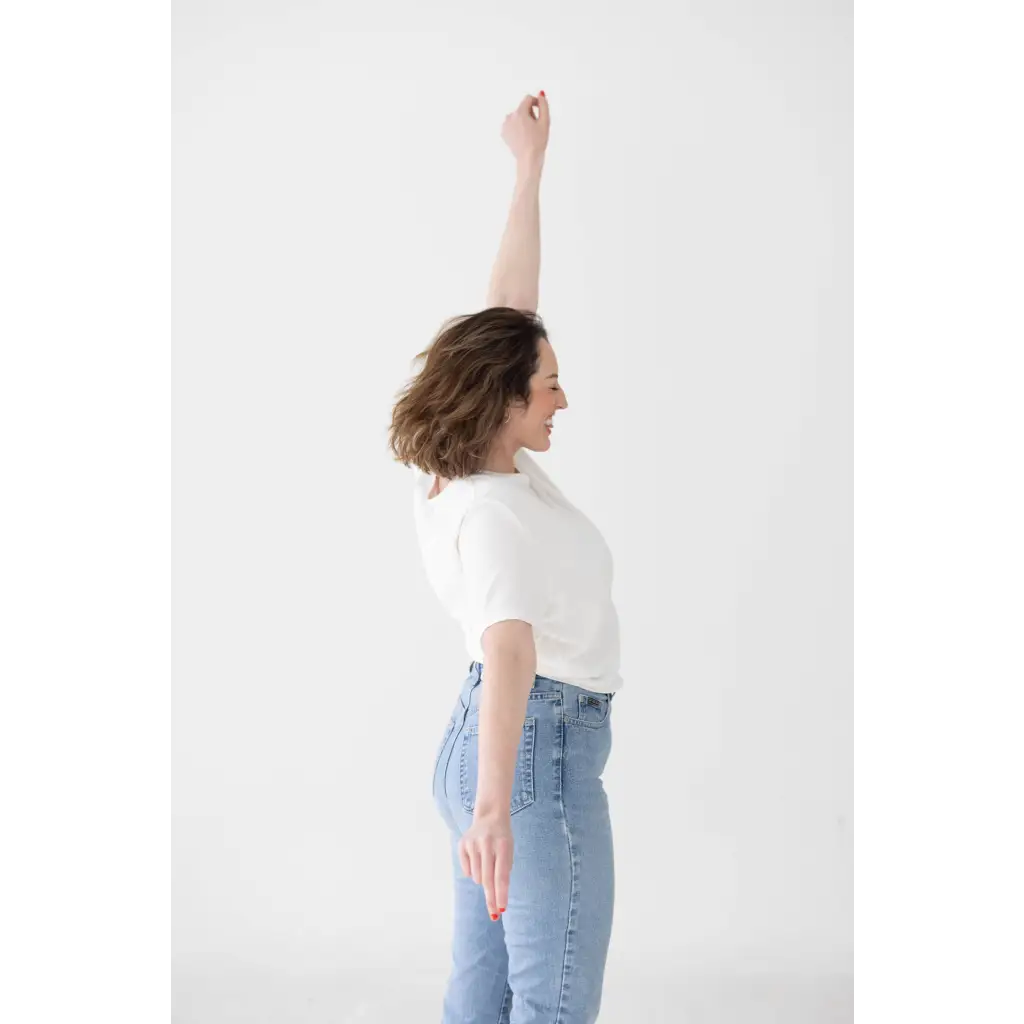 Person in stylish mom crop boxy tee raising arm in victory with light blue jeans