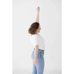 Person in stylish mom crop boxy tee raising arm in victory with light blue jeans