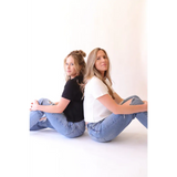 Two women in jeans and T-shirts showing off The Mom Crop boxy tee in Jet Black