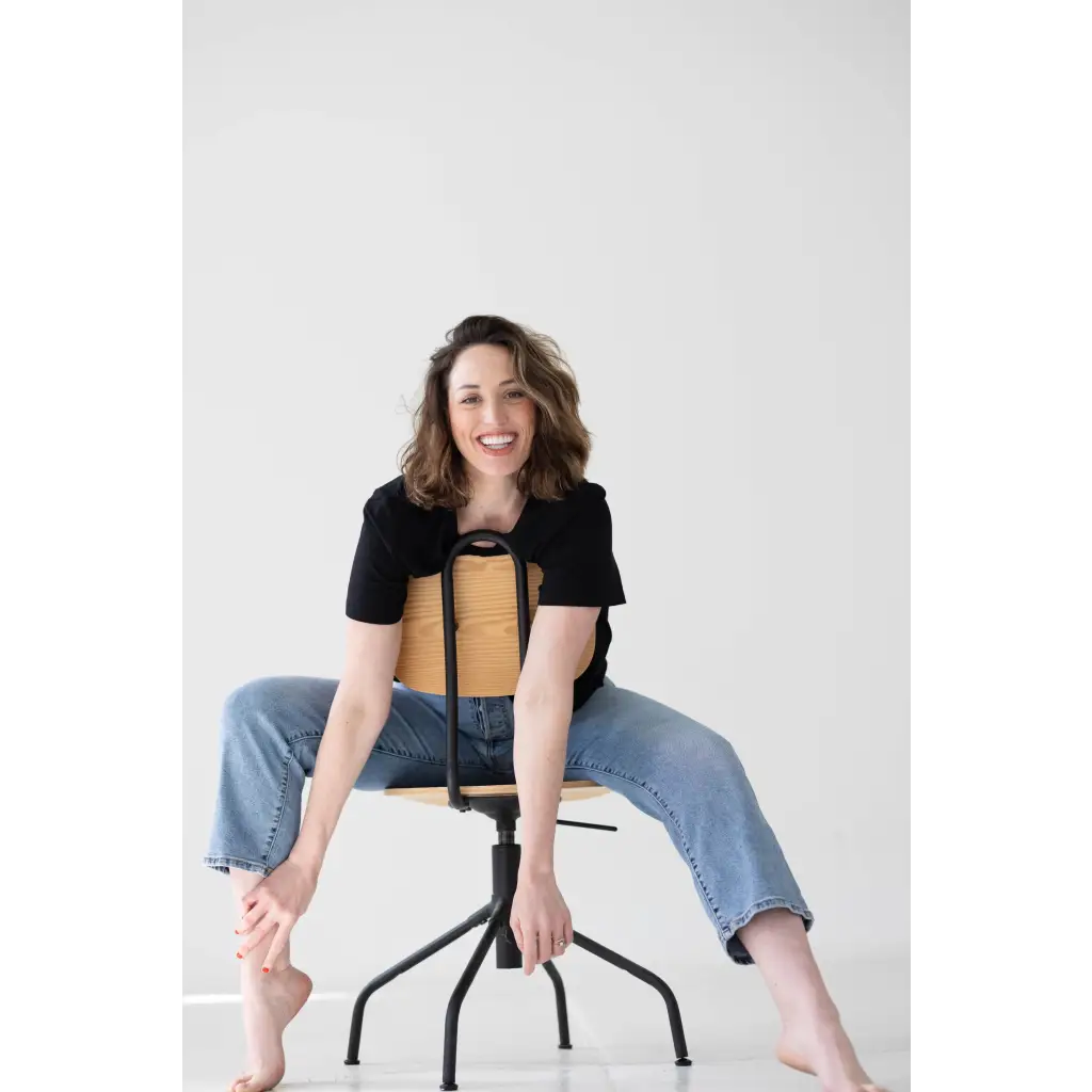 Person sitting on a black metal stool wearing a stylish mom crop boxy tee designed for comfort