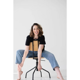 Person sitting on a black metal stool wearing a stylish mom crop boxy tee designed for comfort