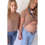 Two women in matching mom crop shirts and jeans, one pregnant, showcasing stylish womens clothes