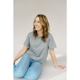 Person smiles in a gray mom crop boxy tee and light blue jeans for casual comfort