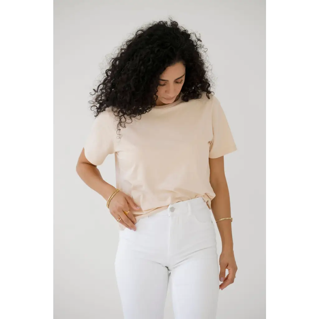 Person in cream mom crop boxy tee and white pants, rocking voluminous curly hair