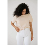 Person in cream mom crop boxy tee and white pants, rocking voluminous curly hair