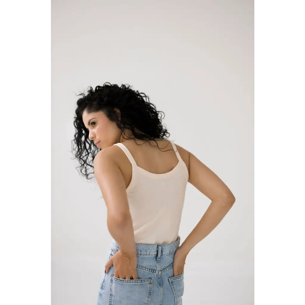 Person in a white mom tank and light blue jeans showcasing trendy transitional tank style