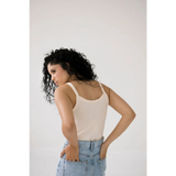 Person in a white mom tank and light blue jeans showcasing trendy transitional tank style