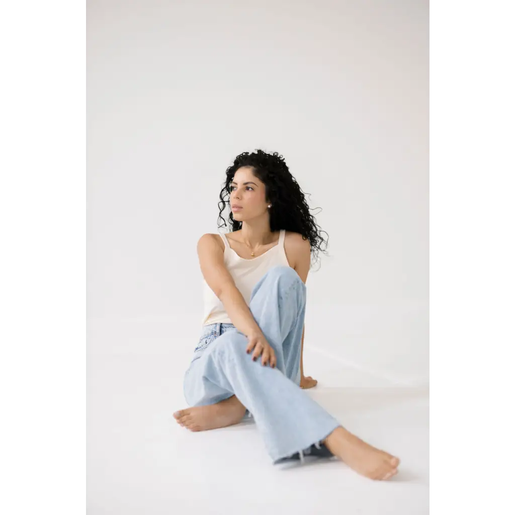 Woman with curly hair in a light blue denim and white mom tank, perfect for any occasion