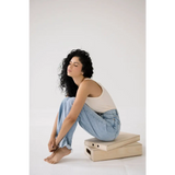 Person with curly dark hair in a white transitional tank and jeans, showcasing mom tank style