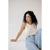 Person in a white transitional tank and light blue jeans showcasing the Mom Tank style