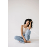 Person with curly hair in a white transitional mom tank and jeans, showing recommended sizing